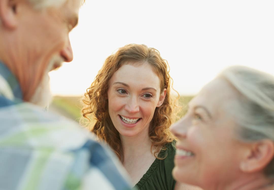 older-couple-talking-with-younger-person-all-smiling older couple talking to a younger person, all smiling