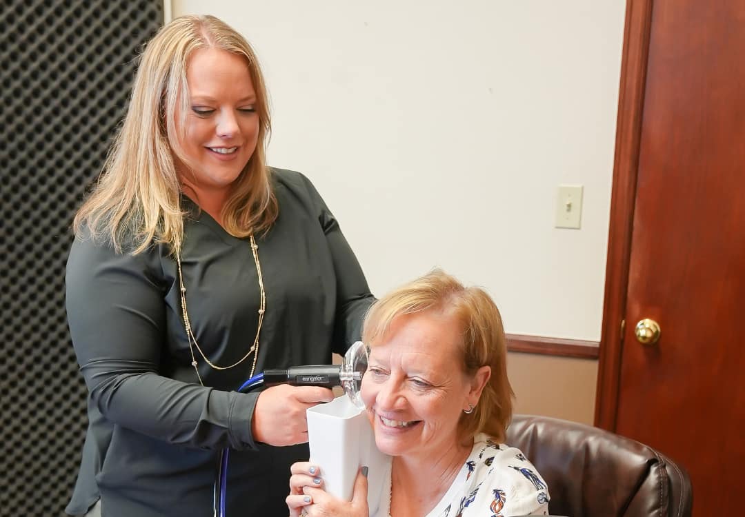 woman-audiologist-cleaning-patients-ears woman cleaning another person's ears